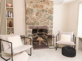 A living room with a fireplace and armchairs at Hendre in Menai Bridge