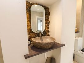 A bathroom with a stone sink and mirror at Hendre in Menai Bridge