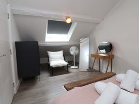 A bedroom with a bed, towels, chair, fan, and wardrobe at Hendre in Menai Bridge