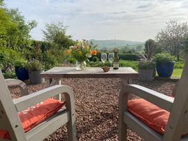 A garden with a table, chairs, flowers, and views at Church Farm Dairy Cadbury near Thorverton