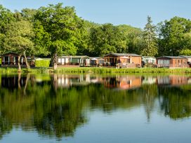 A view of caravans by a lake and trees at Heron in Shobdon