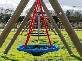 A playground with a swing and climbing frame at Heron in Shobdon