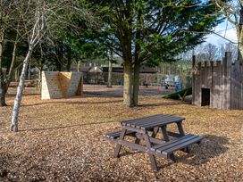 An outdoor play area with a climbing wall and picnic table at Heron Shobdon
