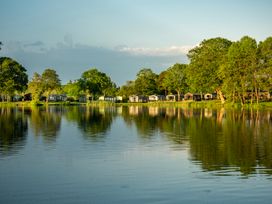 A view of holiday cabins by a lake at Heron in Shobdon