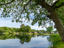 A view of a lake with trees and cabins at Heron in Shobdon