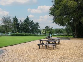 Picnic tables on wood chip ground near a green lawn and trees at Owl in Shobdon