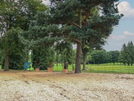 A park area with large trees and potted plants near a metal fence and green grassy fields at Owl in Shobdon