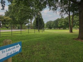 A grassy area with trees and a sign pointing to Lakeside Bar and 1st Tee at Owl in Shobdon