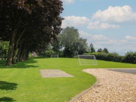 A grassy field with two small soccer goals and trees along the side at Owl in Shobdon