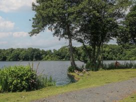 A lakeside scene with trees geese and a gravel path at Owl in Shobdon