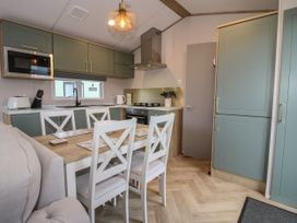A kitchen and dining area with green cabinets white chairs and a wooden table at Owl in Shobdon