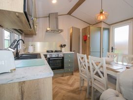 A kitchen and dining area with a stove oven dining table and chairs at Owl in Shobdon