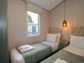 A bedroom with two single beds green wardrobes and a window at Owl in Shobdon