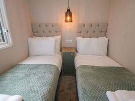A bedroom with two single beds separated by a bedside table and a hanging light at Owl in Shobdon