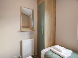 A bedroom corner with a wooden wardrobe, a mirror above a radiator, and a bed with folded towels at Owl in Shobdon