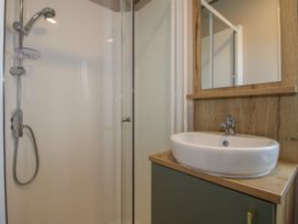 A bathroom with a shower enclosure and a sink with a mirror above at Owl in Shobdon