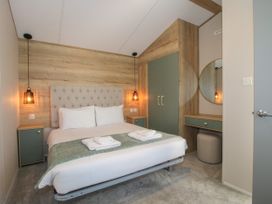 A bedroom with a double bed two bedside tables hanging lamps a wardrobe and a vanity area with a round mirror and stool at Owl in Shobdon