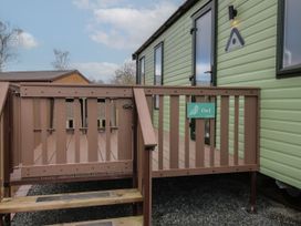 An exterior view of a green mobile home with a brown wooden deck and gate with a sign reading Owl at Owl in Shobdon