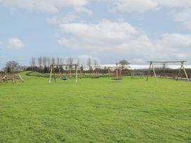 A playground with swings and climbing equipment on a grassy field at Owl in Shobdon