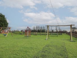 A playground with swings and climbing structures on grass at Owl in Shobdon