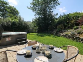 A garden with a hot tub and dining table set for tea at Felin Gogoyan in Tregaron