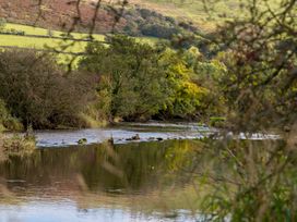A view of a river with trees and hills at Felin Gogoyan Tregaron
