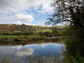 A river with trees and hills in the background at Felin Gogoyan Tregaron
