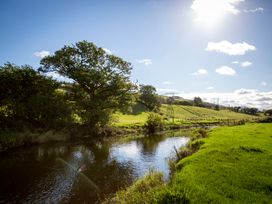 A river with trees and hills under a clear sky at Felin Gogoyan Tregaron