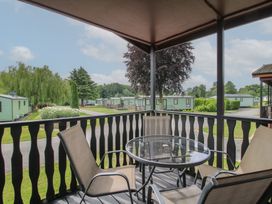 An outdoor area with a table and chairs overlooking caravans at Snowdrop in Eardisland