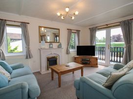 A living room with sofa, television and coffee table at Snowdrop in Eardisland