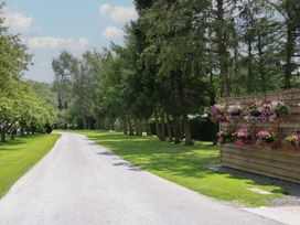 A gravel road lined with trees and flower boxes at Snowdrop in Eardisland
