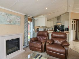 A living room with recliner chairs and kitchen area at Daisy in Eardisland
