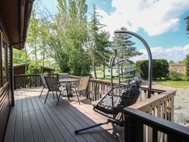 An outdoor deck with a hanging chair and table in Foxglove Eardisland