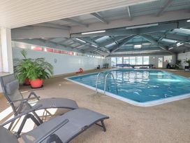 An indoor swimming pool with deck chairs and plants at Three Views Lodge Whitsand Bay Fort Holiday Village