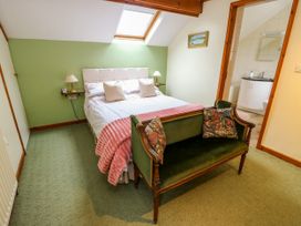 A bedroom with a bed and a couch at The Cottage at Ty Newydd in Brynsiencyn