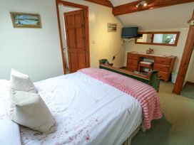 A bedroom with a bed and a dresser at The Cottage at Ty Newydd in Brynsiencyn