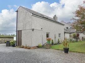 An exterior view of a house with planters and a driveway at The Cottage at Ty Newydd in Brynsiencyn