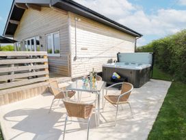 An outdoor area with a hot tub and seating at Heritage Retreat in Monknash