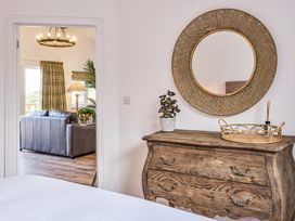 A bedroom with a wooden dresser and a mirror at Heritage Retreat in Monknash
