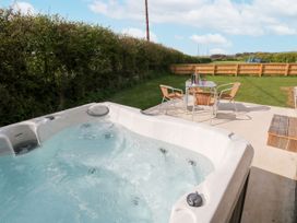 An outdoor area with a hot tub and a table with chairs at Heritage Retreat Monknash