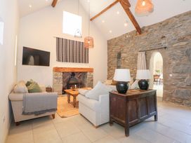 A living room with stone walls a fireplace a wooden coffee table sofas and two lamps on a wooden sideboard at Ysgubor Maen Y Bardd in Rowen near Conwy