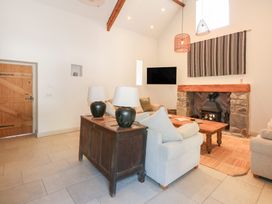 A living room with sofas a wooden coffee table a stone fireplace and a wooden sideboard with lamps at Ysgubor Maen Y Bardd in Rowen near Conwy