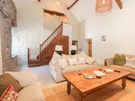 A living room with sofas and a wooden coffee table near a wooden staircase at Ysgubor Maen Y Bardd Rowen near Conwy