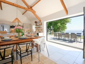 A kitchen and dining area with wooden beams and a table set with dishes and glasses at Ysgubor Maen Y Bardd in Rowen near Conwy