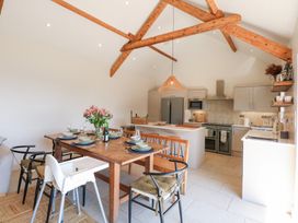 A dining table set with plates and glasses in a kitchen with wooden beams on the ceiling at Ysgubor Maen Y Bardd in Rowen near Conwy