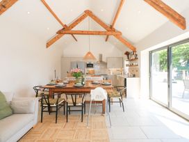 An open kitchen and dining area with a wooden dining table set for six and exposed wooden ceiling beams at Ysgubor Maen Y Bardd in Rowen near Conwy