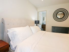 A bedroom with a bed a nightstand a lamp a round mirror above a radiator at Ysgubor Maen Y Bardd in Rowen near Conwy