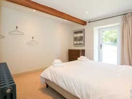 A bedroom with a bed and white bedding towels on the bed wooden chest of drawers a framed picture on the wall and a door leading outside at Ysgubor Maen Y Bardd Rowen near Conwy