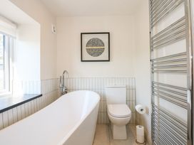 A bathroom with a bathtub toilet towel rack and a window at Ysgubor Maen Y Bardd Rowen near Conwy
