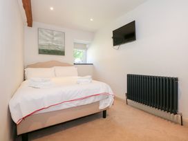 A bedroom with a bed and folded towels a wall-mounted television and a radiator at Ysgubor Maen Y Bardd Rowen near Conwy